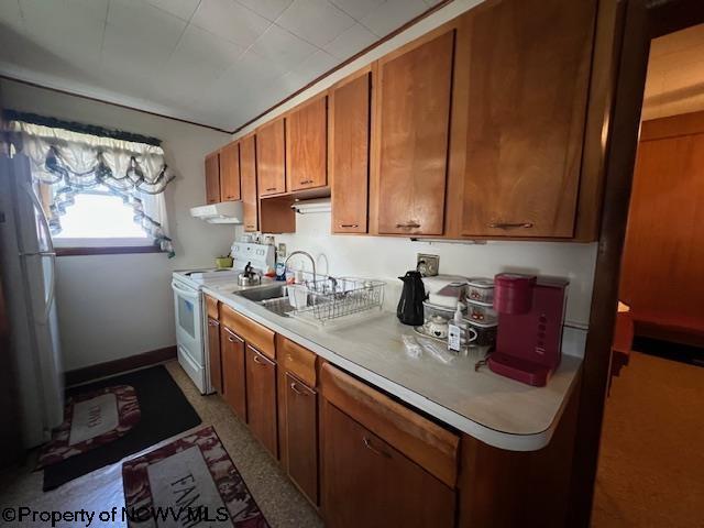 kitchen with brown cabinetry, white appliances, light countertops, and under cabinet range hood