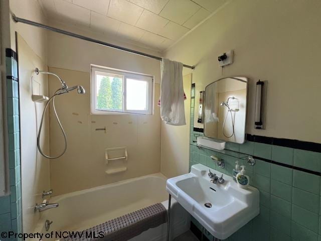 full bath featuring shower / bath combination with curtain, a sink, and tile walls