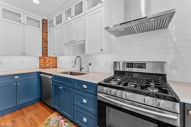 kitchen featuring light hardwood / wood-style flooring, wall chimney exhaust hood, appliances with stainless steel finishes, decorative backsplash, and sink