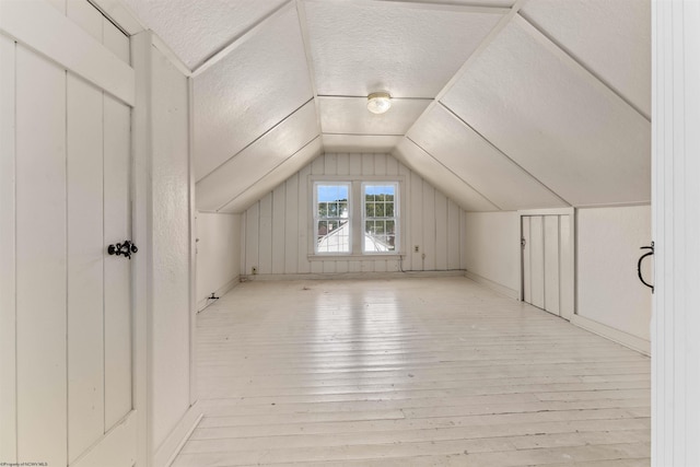 additional living space featuring light wood-type flooring and lofted ceiling