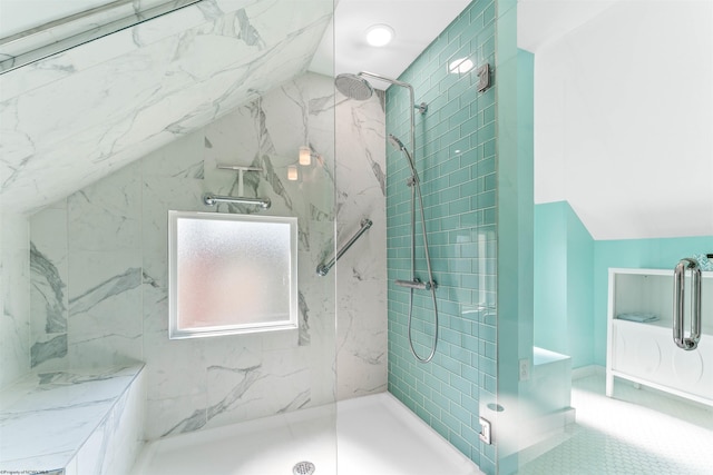 bathroom with tiled shower, tile patterned floors, vaulted ceiling, and tile walls