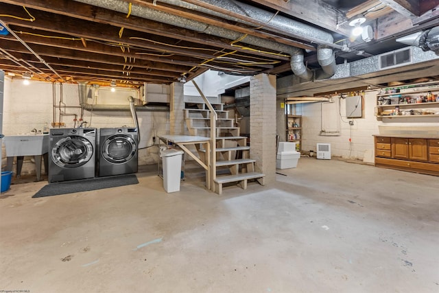 basement featuring electric panel, washer and clothes dryer, and sink