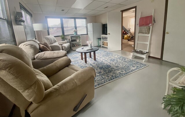 living room with concrete floors and a paneled ceiling