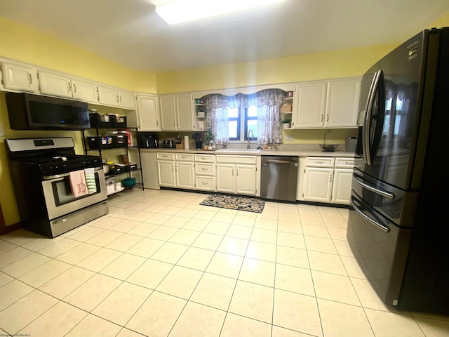 kitchen with sink, appliances with stainless steel finishes, light tile patterned floors, and white cabinetry