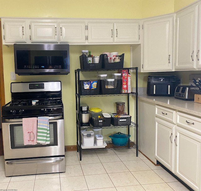 kitchen with light tile patterned flooring, stainless steel appliances, and white cabinets