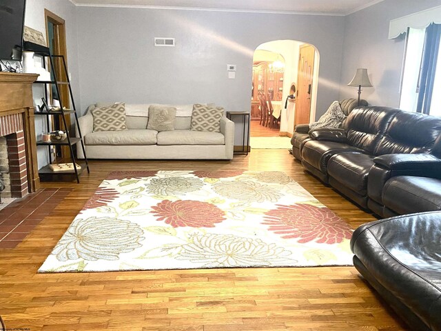 living room featuring wood-type flooring, a fireplace, and crown molding