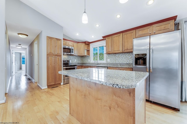 kitchen featuring tasteful backsplash, a kitchen island, light hardwood / wood-style floors, appliances with stainless steel finishes, and vaulted ceiling