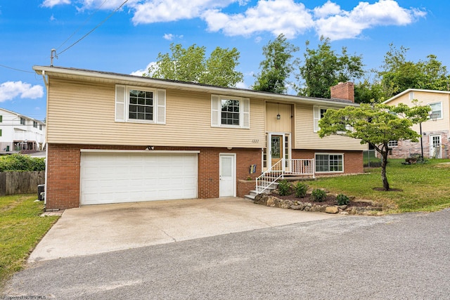 raised ranch featuring a garage and a front yard