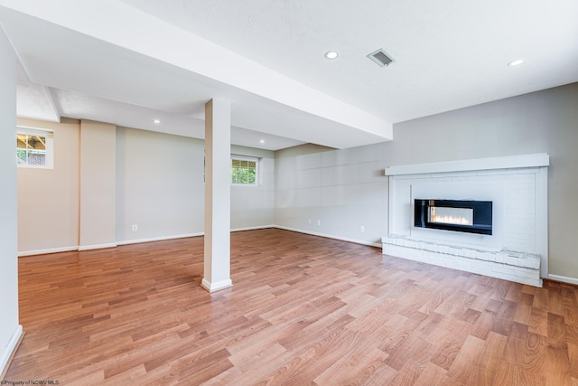 unfurnished living room featuring a multi sided fireplace and light hardwood / wood-style flooring