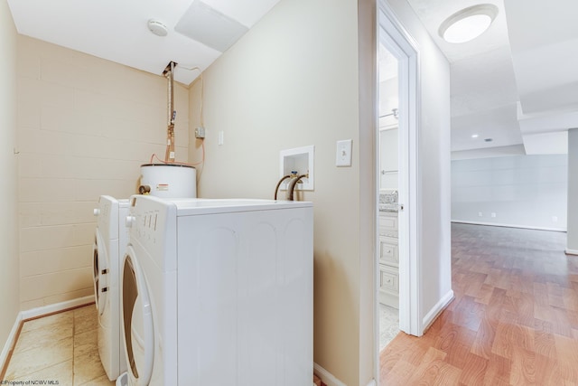 laundry area with light hardwood / wood-style flooring, washer and dryer, and water heater