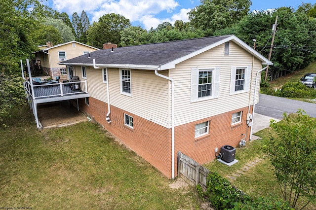 view of property exterior featuring central AC unit, a wooden deck, and a lawn