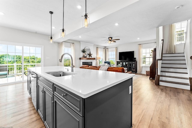 kitchen featuring a center island with sink, decorative light fixtures, a wealth of natural light, and light hardwood / wood-style floors