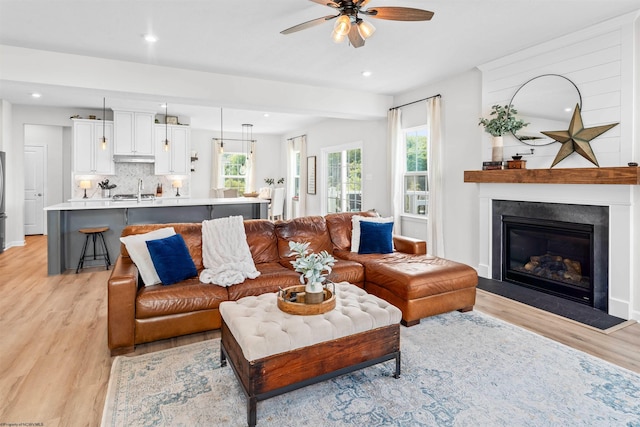 living room with sink, ceiling fan, and light hardwood / wood-style floors