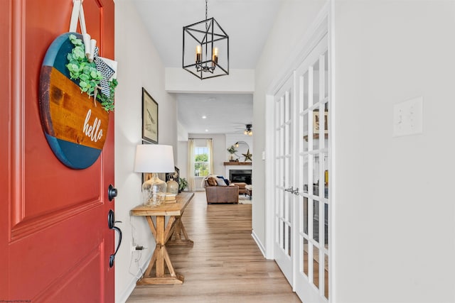 foyer with ceiling fan with notable chandelier and light wood-type flooring