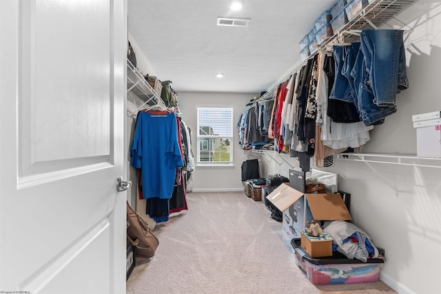 walk in closet featuring light colored carpet