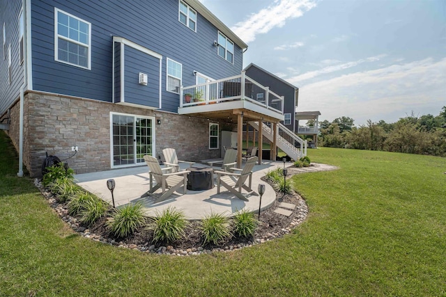 rear view of house with a patio, a wooden deck, an outdoor fire pit, and a yard