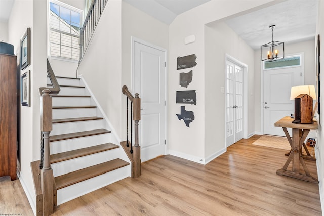 foyer entrance with light hardwood / wood-style flooring, plenty of natural light, and a notable chandelier