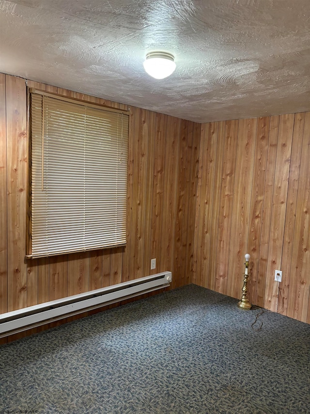 unfurnished room featuring wooden walls, a textured ceiling, carpet, and baseboard heating