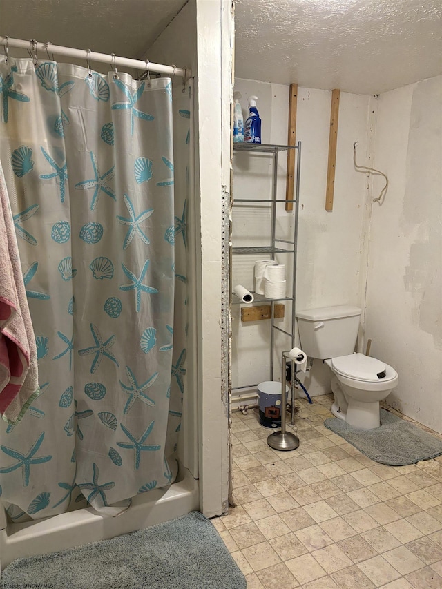 full bathroom with toilet, a stall shower, and a textured ceiling
