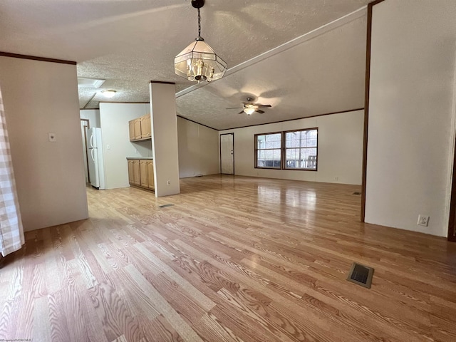 unfurnished living room with ceiling fan with notable chandelier, ornamental molding, light hardwood / wood-style floors, and a textured ceiling