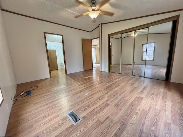 unfurnished bedroom with crown molding, lofted ceiling, light wood-type flooring, and a closet