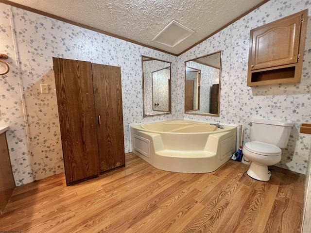 bathroom featuring a washtub, crown molding, hardwood / wood-style floors, a textured ceiling, and toilet