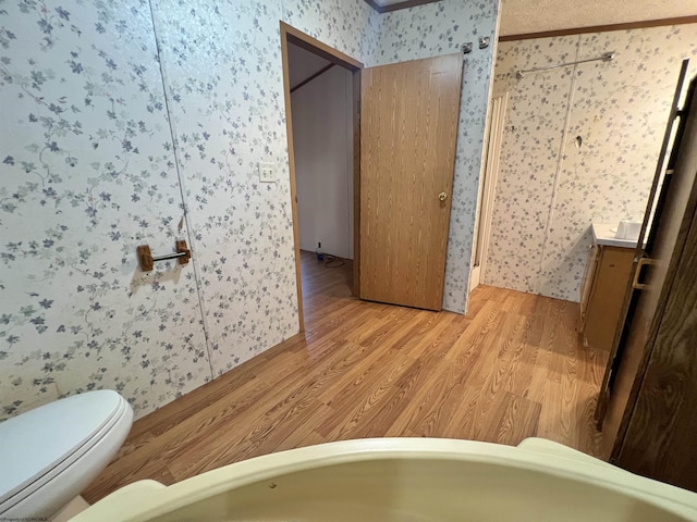 bathroom featuring crown molding, toilet, and hardwood / wood-style floors