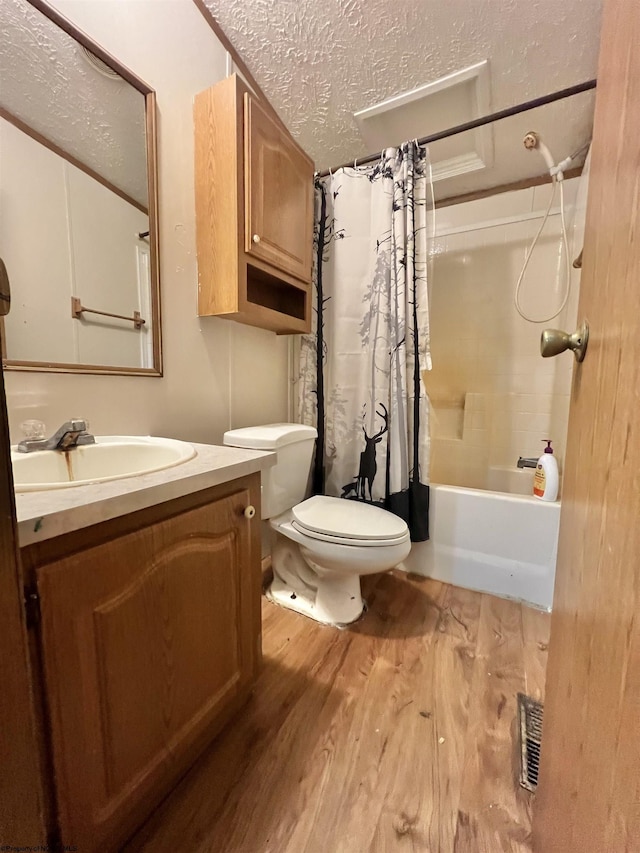 full bathroom with wood-type flooring, vanity, shower / tub combo, toilet, and a textured ceiling