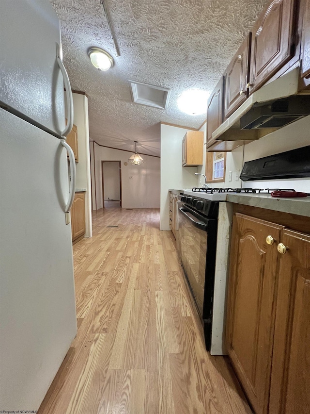 kitchen featuring black range with gas cooktop, hanging light fixtures, a textured ceiling, white refrigerator, and light wood-type flooring