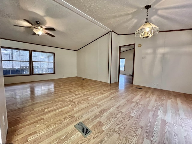 unfurnished room with lofted ceiling, a textured ceiling, ornamental molding, light hardwood / wood-style floors, and ceiling fan with notable chandelier