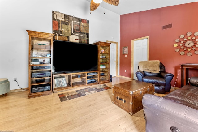 living area with visible vents, a ceiling fan, wood finished floors, high vaulted ceiling, and baseboards