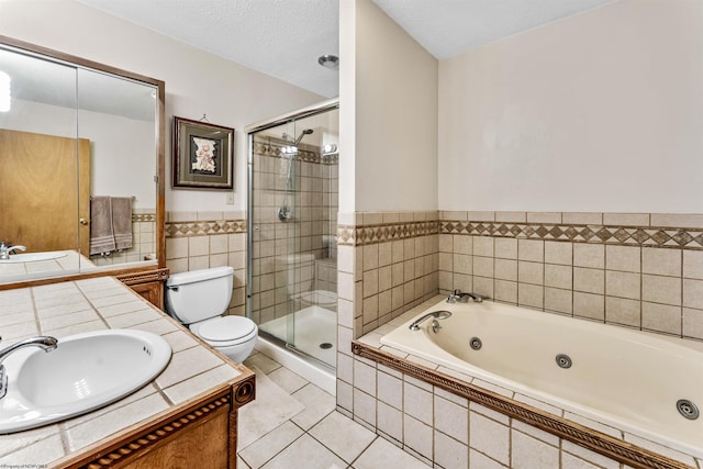 full bathroom with toilet, a tub with jets, tile patterned flooring, a textured ceiling, and vanity