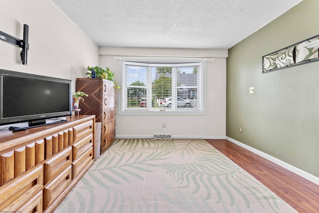 living room featuring a textured ceiling, wood finished floors, visible vents, and baseboards