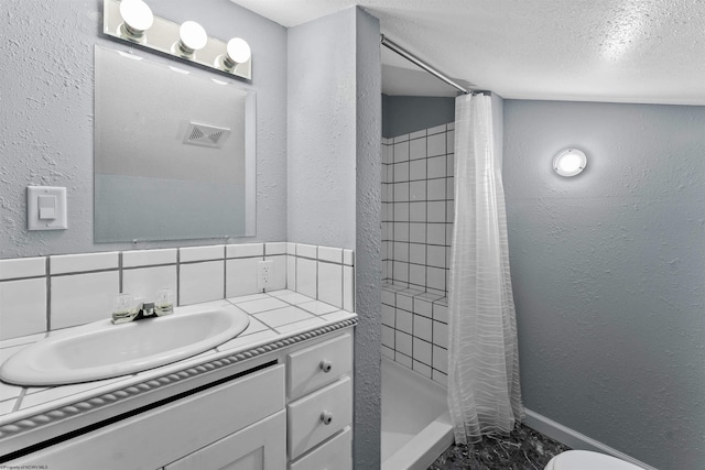 bathroom featuring a stall shower, tasteful backsplash, vanity, and a textured wall