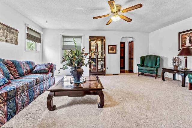 living room with a textured ceiling, ceiling fan, and carpet floors