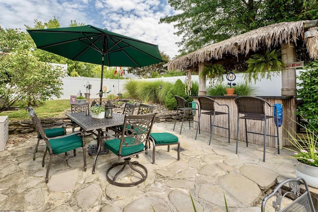 view of patio featuring outdoor dry bar, outdoor dining space, and fence