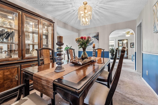 dining space with arched walkways, a chandelier, a textured ceiling, and light colored carpet