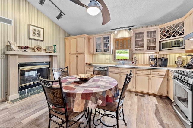 kitchen featuring glass insert cabinets, appliances with stainless steel finishes, light countertops, and a textured ceiling