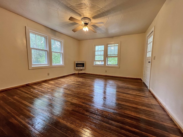 empty room with heating unit, a healthy amount of sunlight, ceiling fan, and hardwood / wood-style floors