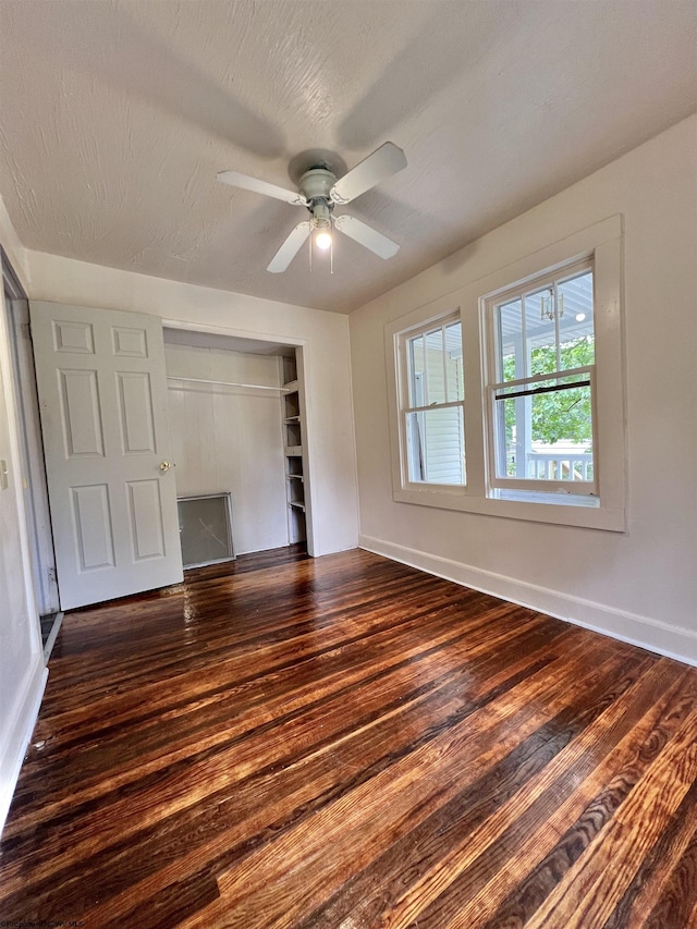 unfurnished bedroom featuring a textured ceiling, baseboards, dark wood finished floors, and a closet