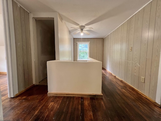 spare room with ceiling fan, wooden walls, and dark wood-style flooring