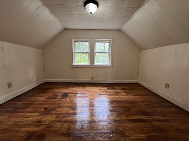 additional living space featuring lofted ceiling, dark wood finished floors, and baseboards