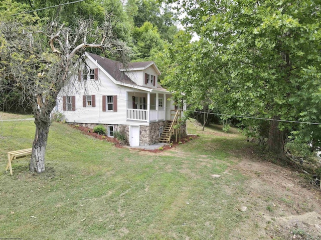 view of side of home with covered porch, a lawn, and stairs