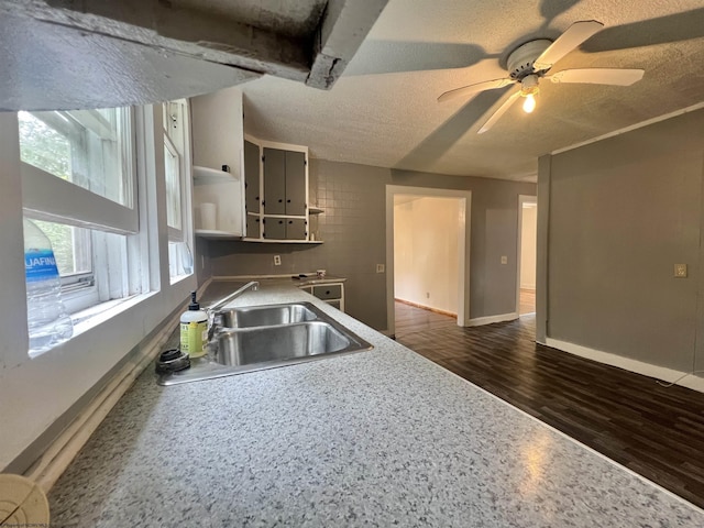 kitchen featuring dark wood finished floors, a sink, a textured ceiling, and open shelves