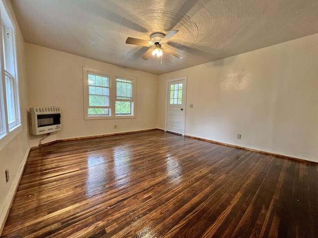 unfurnished living room featuring a textured ceiling, a ceiling fan, baseboards, heating unit, and dark wood finished floors