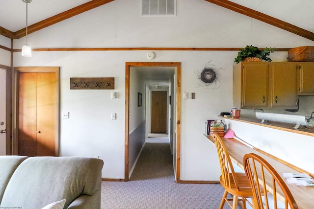 kitchen featuring light carpet, vaulted ceiling with beams, and decorative light fixtures