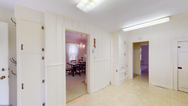 hallway with light tile patterned flooring and an inviting chandelier