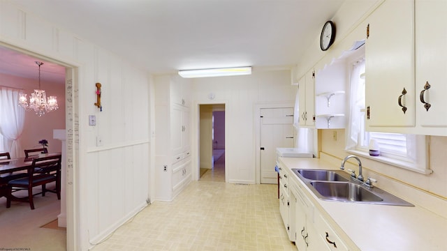 kitchen with white cabinets, sink, light tile patterned floors, and an inviting chandelier