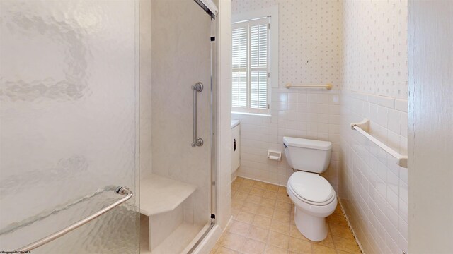 bathroom with toilet, a shower with shower door, tile walls, tile patterned floors, and vanity