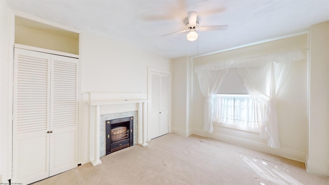 unfurnished living room with ceiling fan, light carpet, and a tile fireplace